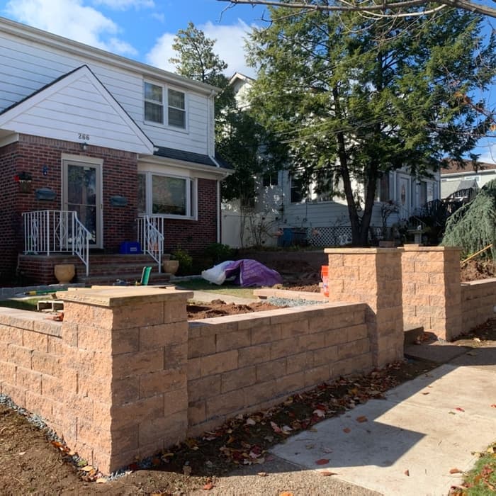 New tan retaining wall being built in front of a suburban house.