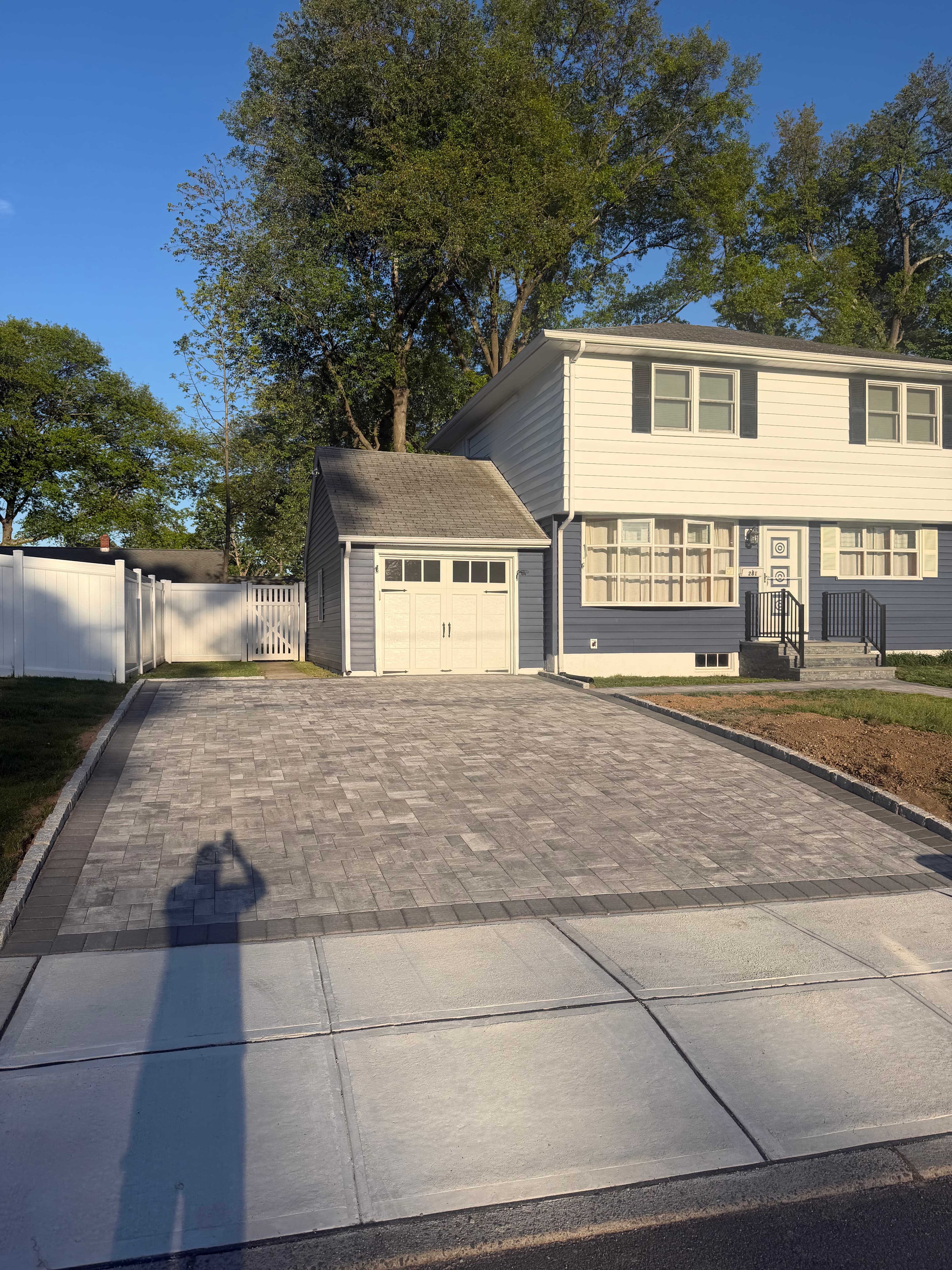 Fresh gray paver driveway with bordered edges in front of a suburban house.