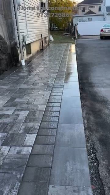 Finished stamped walkway beside a retaining wall and concrete sidewalk with small steps.
