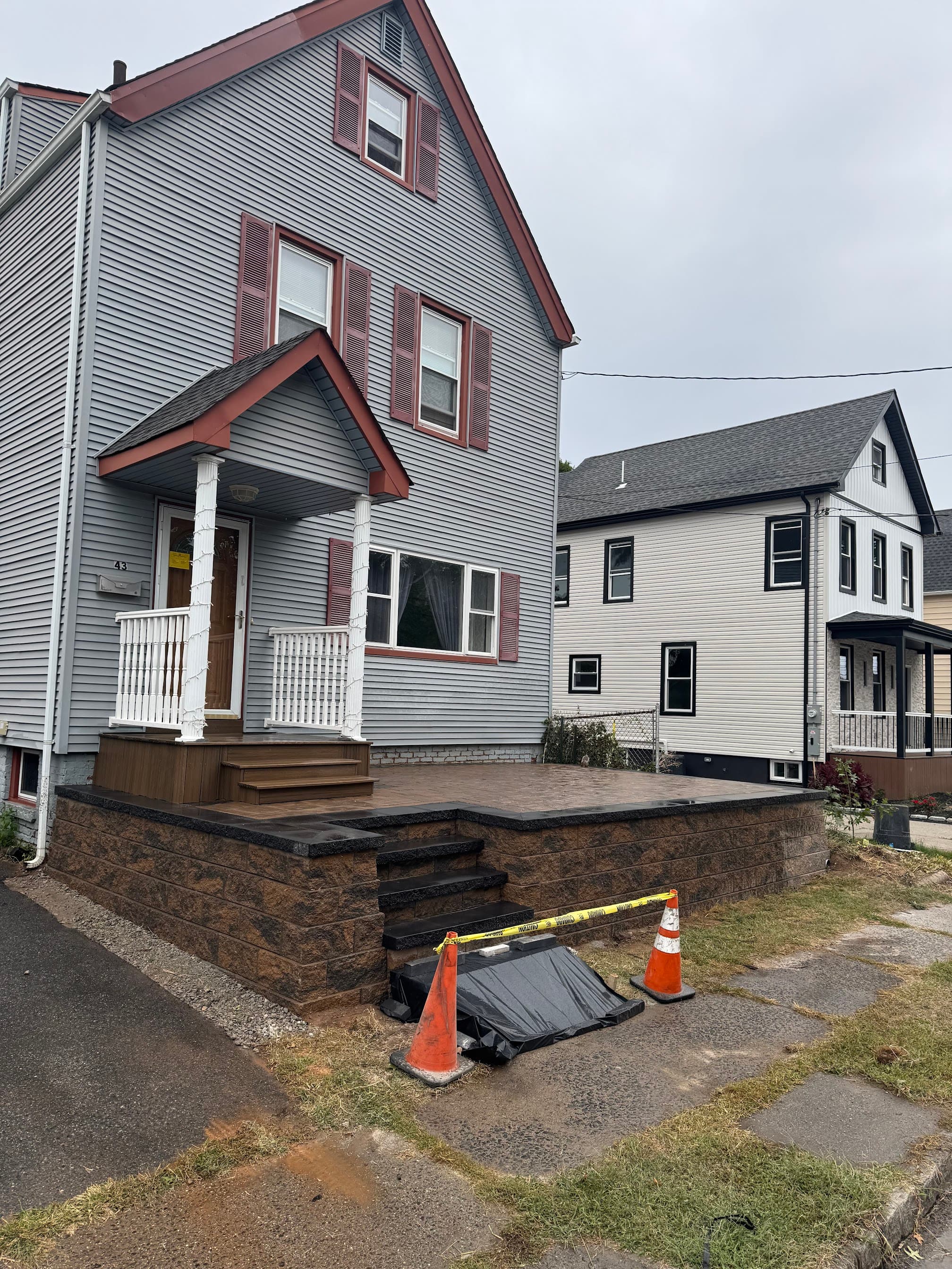 Raised front porch with stone-look retaining wall, paver landing, and fresh exterior trim on a house.