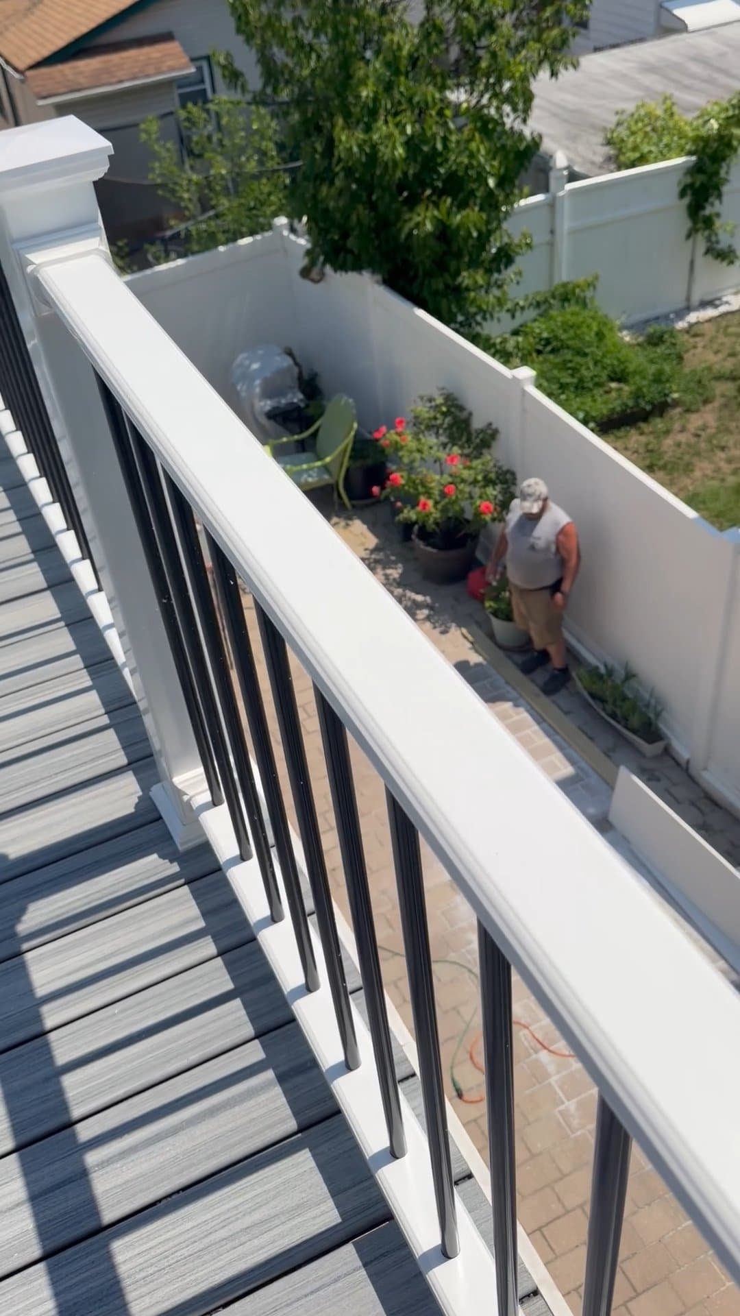 Gray rooftop deck with white posts and black railings on a sunny day.