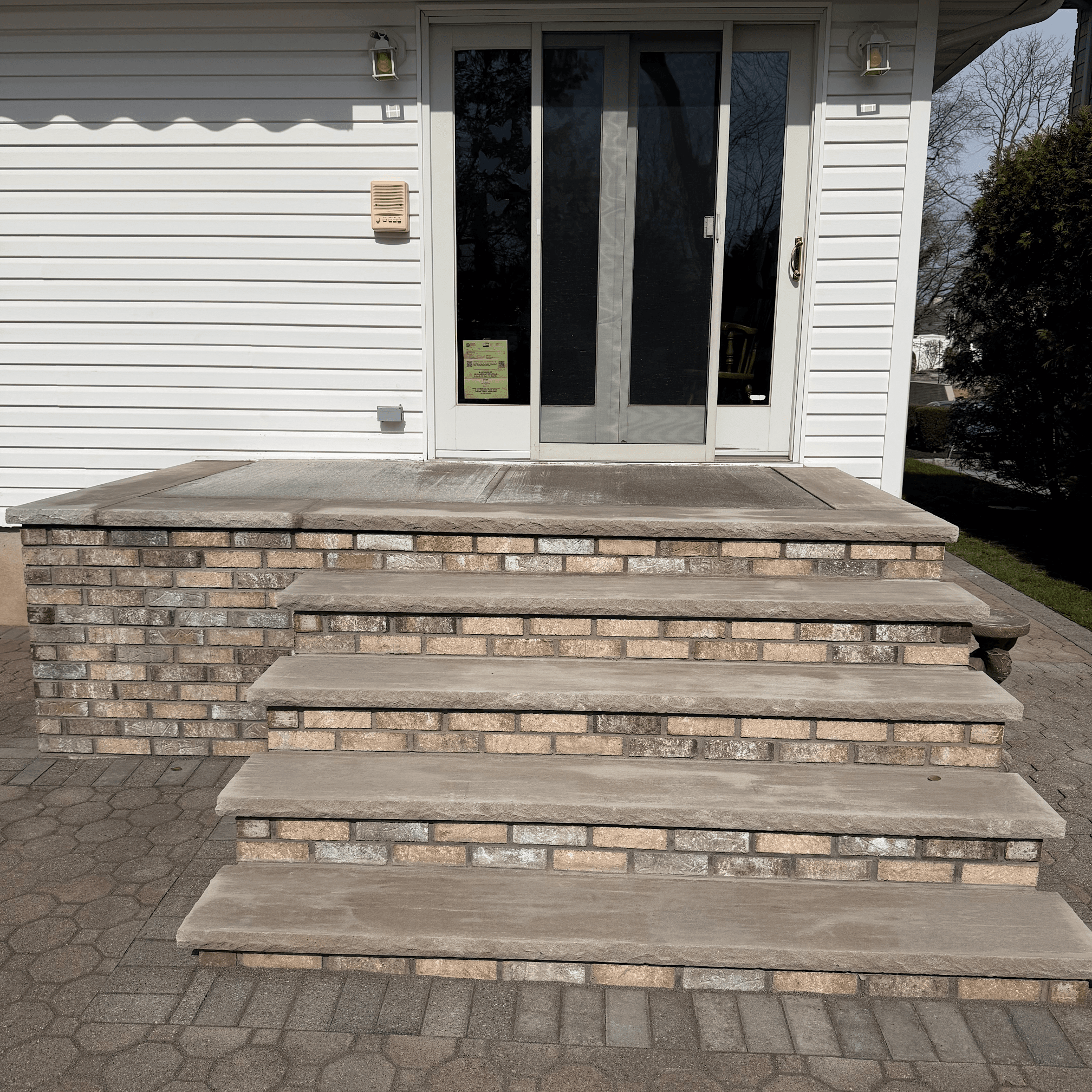 Brick and concrete front steps leading to a residential sliding glass door.