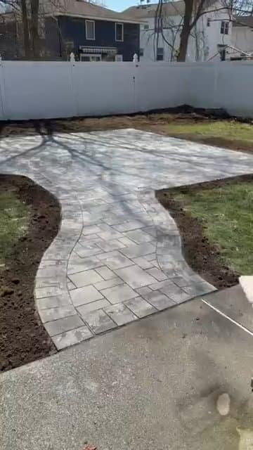New gray paver patio and walkway installed in a backyard near a pool.