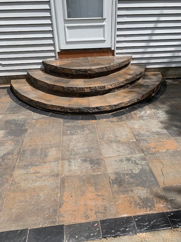 Curved natural stone front steps leading to a door with a matching stone patio.