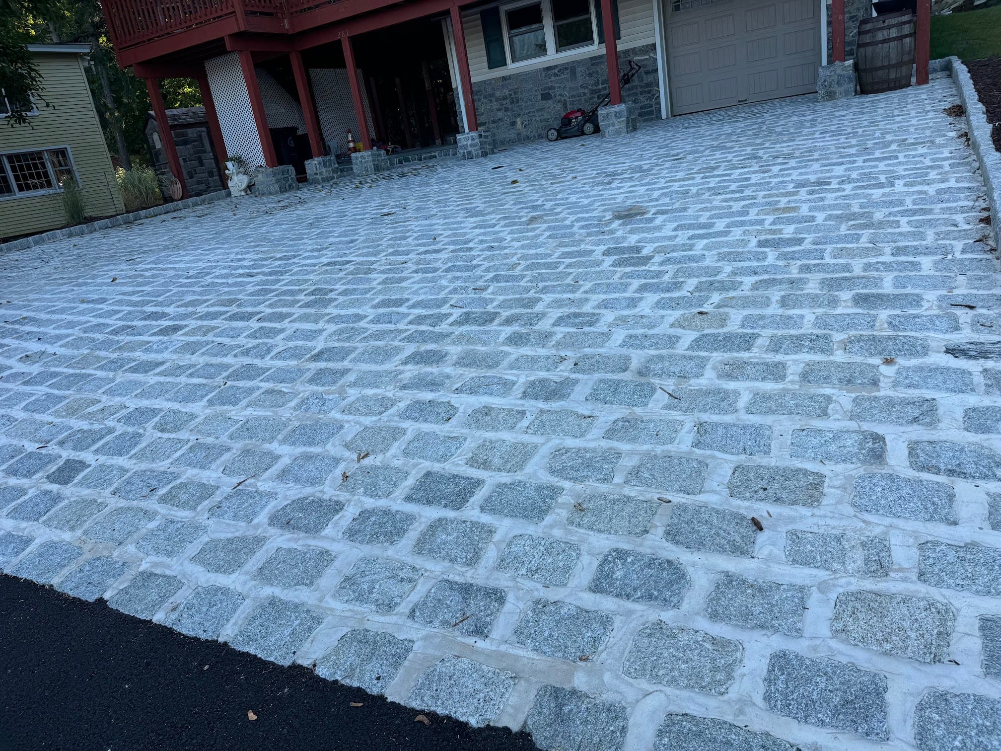 Gray cobblestone driveway with mortar joints leading to a home garage.