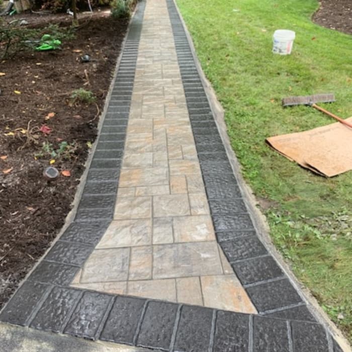Newly installed stone garden walkway with dark border edging in a landscaped yard.